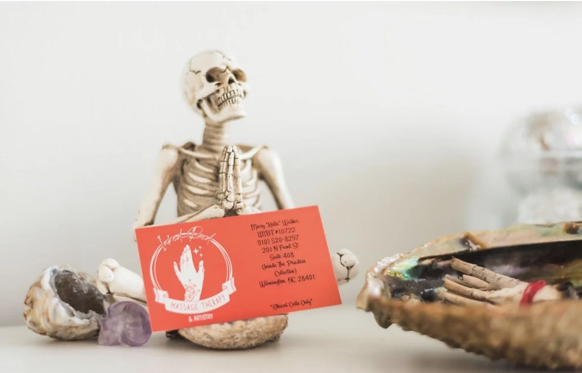 Skeleton figurine holding an Inked Red business card