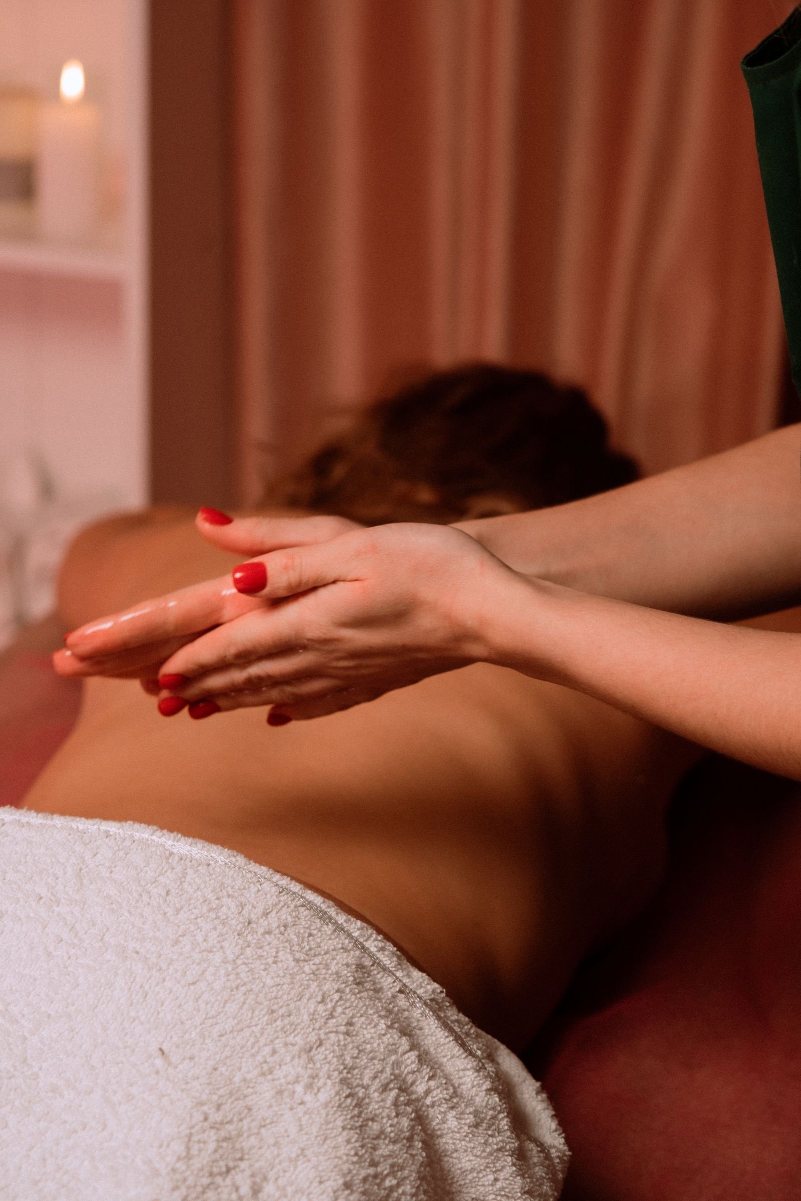 Therapist's hands ready to begin a massage, warm red studio light