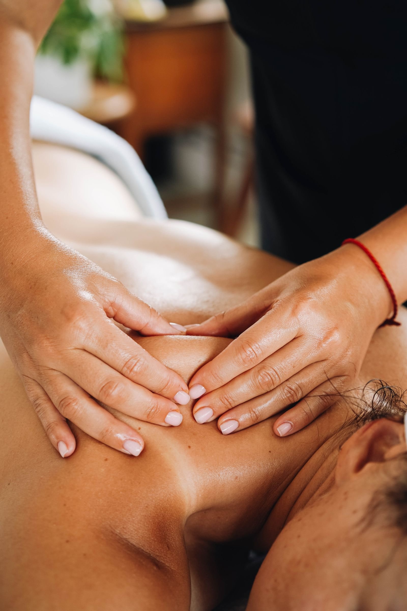 Therapist's hands digging into deep tissue on a client's upper back